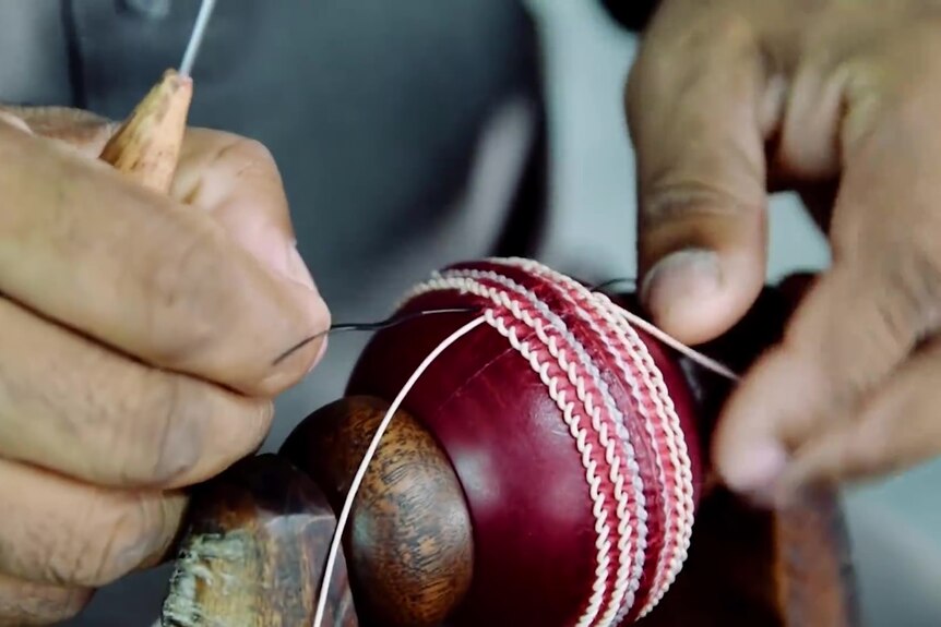 The seams on a cricket ball being sewn by hand.