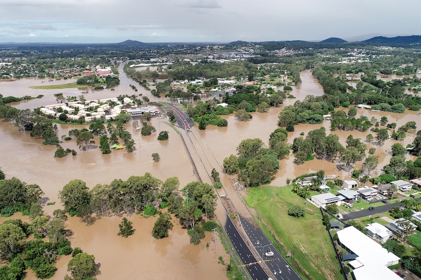 Aerial shot of flooded buildings, trees and a bridge.
