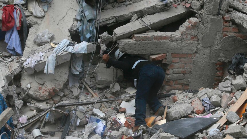 A person searches the rubble of a collapsed building.