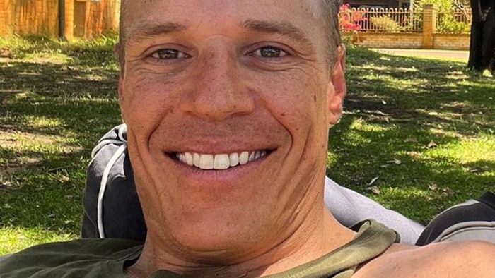 A tight selfie shot of a man smiling outdoors.