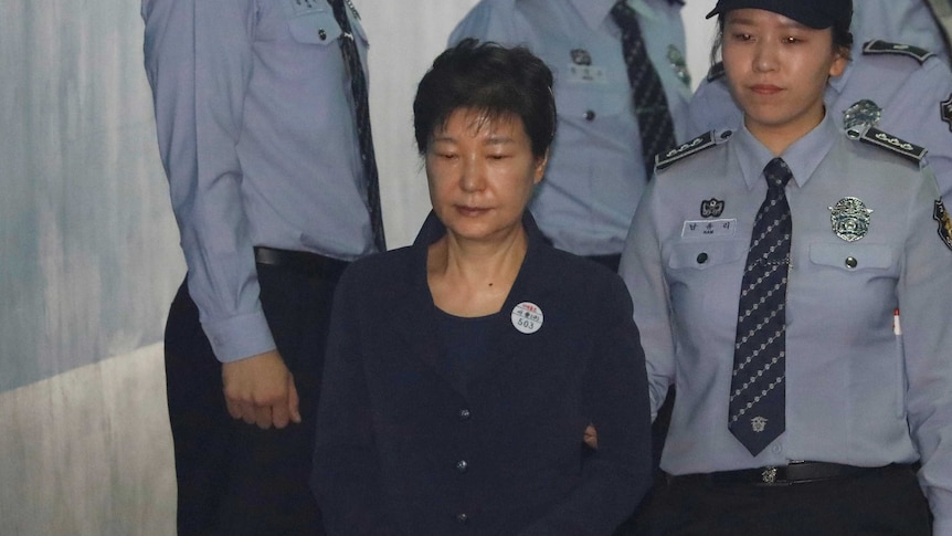 An officer leads Park Geun-hye into the courtroom.