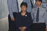 An officer leads Park Geun-hye into the courtroom.