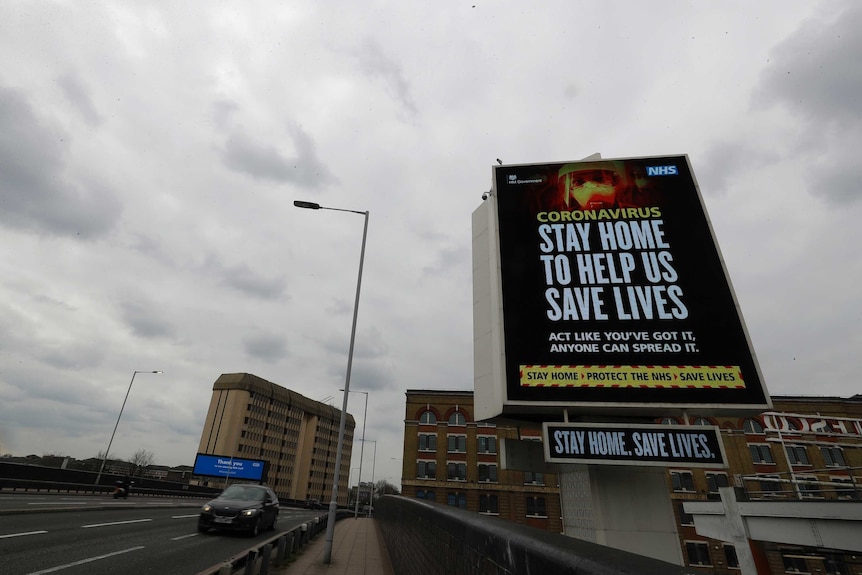 A billboard on the side of a highway reads "Stay home to help save lives"