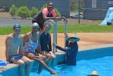 A group of multi cultural swimmers smile from the pool.