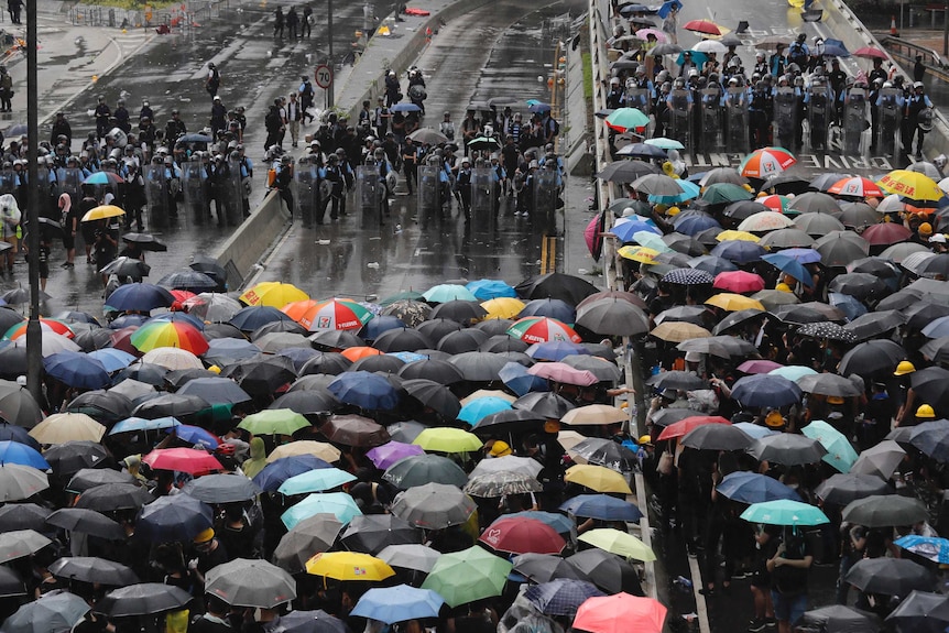 Protesters holding umbrellas face off against riot police in Hong Kong.