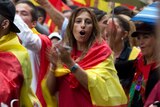 A woman draped in the Spanish flag joins other pro-Spanish unity demonstrators in clapping on Barcelona street