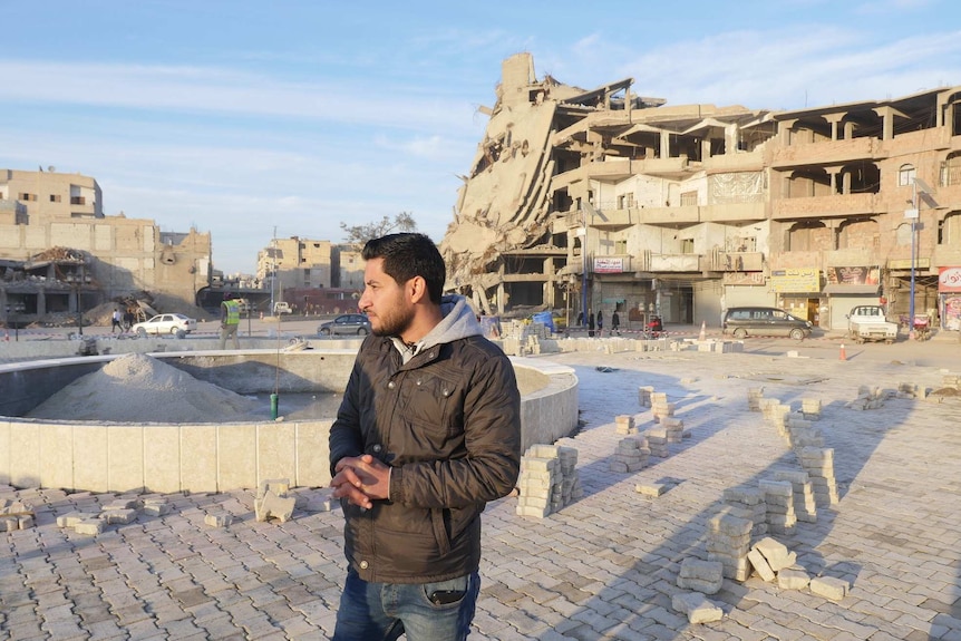 A man looks around the rubble left in a destroyed public square