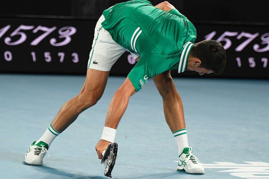 Novak Djokovic smashes his racquet against the court on Rod Laver Arena during the Australian Open.