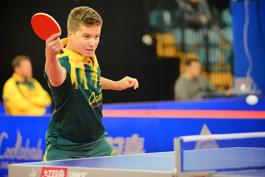 Table tennis champion Wade Townsend dressed in the green and gold Australian uniform hitting a ball during a match.