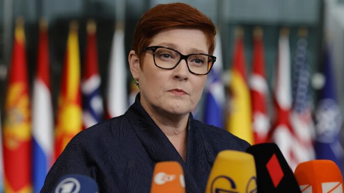 Photo of woman in glasses with flags in the background