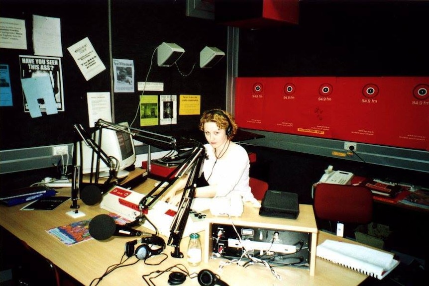 Woman in radio studio behind a microphone.