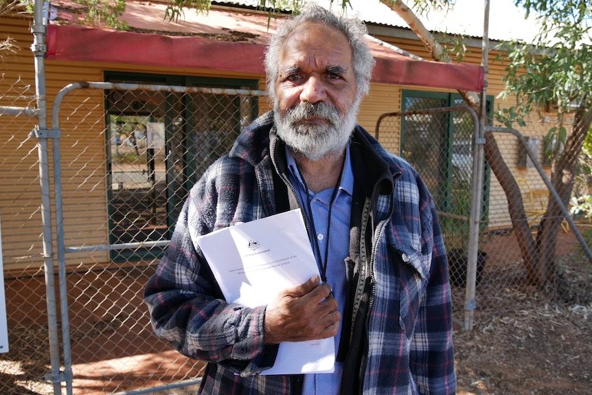 An Indienous man holds a report