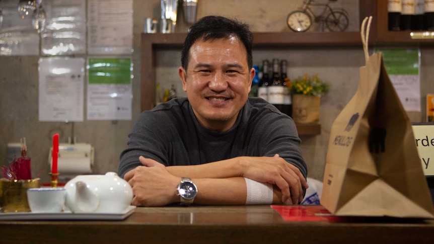 a man smiling as he leans over a counter top