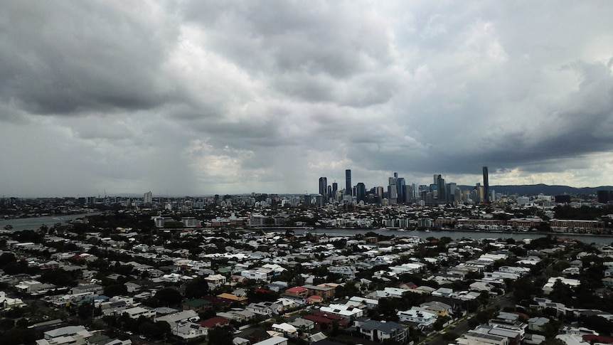 Brooding clouds over the Brisbane CBD. Suburbia stretches in all directions.