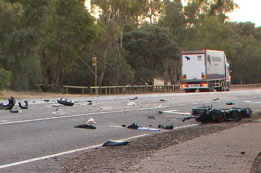 A motorcycle crashed into pieces with a truck on the other side of the road