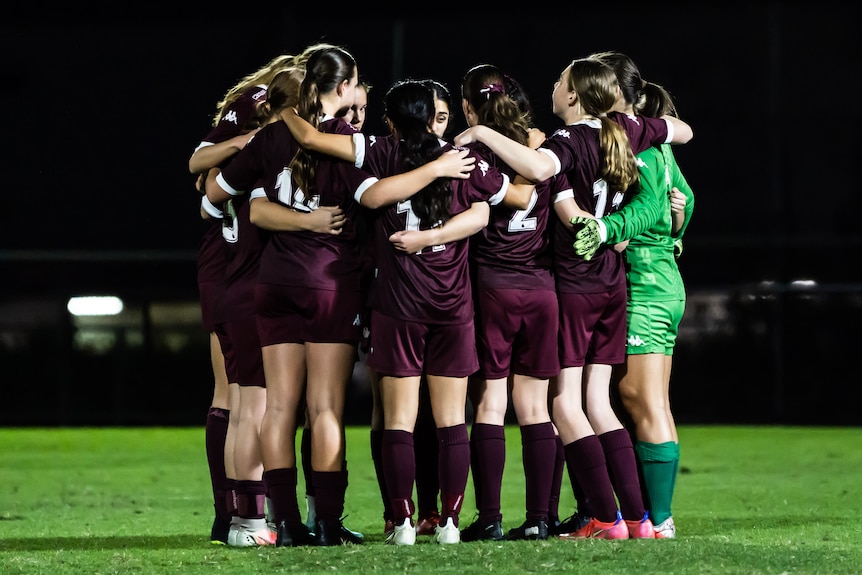 a group of female soccer players in a team huddle