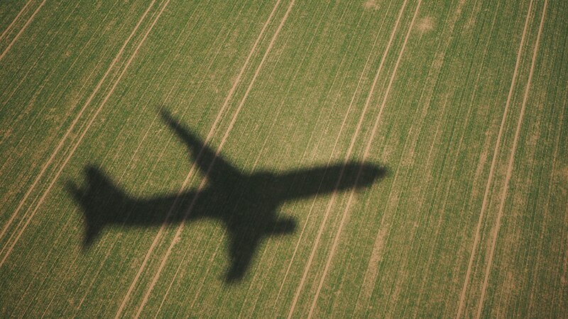 Shadow of a plane taking off over grassland.