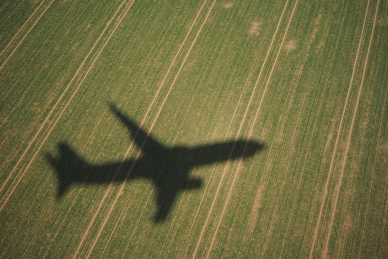 Shadow of a plane taking off over grassland.