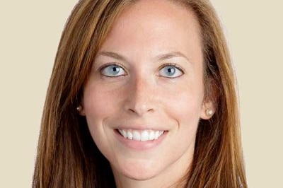 A close-up shot of a woman with bright blue eyes and a wide smile, looking straight ahead.