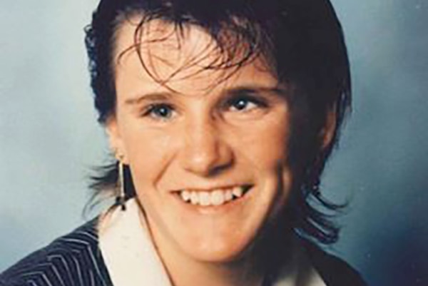 A profile shot of a smiling Radina Djukich posing for a photo in a studio wearing a white shirt and dark vest.