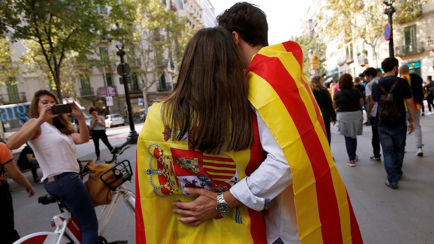 Friends wrapped in Catalan and Spanish flags walk through Barcelona following the independence vote.