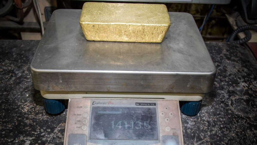 Gold bar on scales being weighed