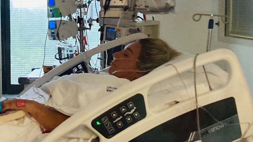 A woman, seen in profile, lies in a hospital bed, intubated.
