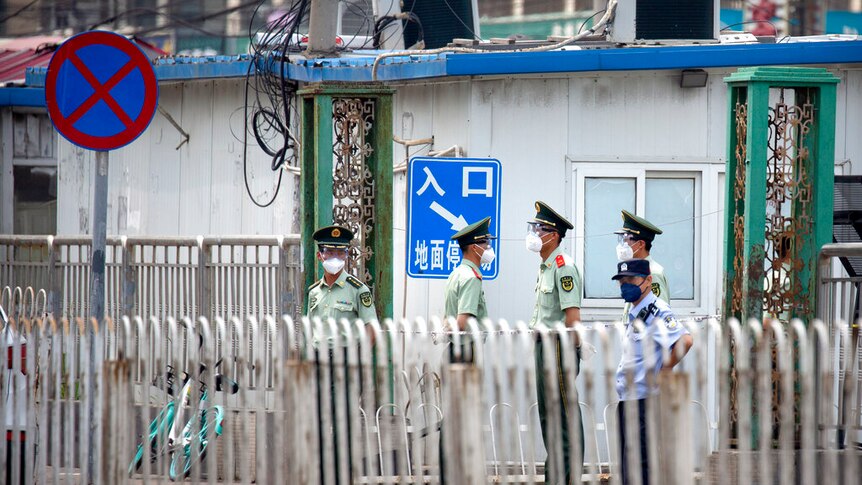 Paramilitary police stand guard on a street near the Xinfadi wholesale food market district in Beijing, Saturday, June 13, 2020.