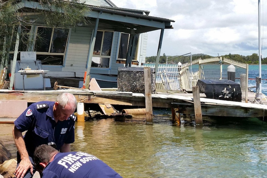 Fire and Rescue NSW officers in foreground of photo with the sinking restaurant in the background.