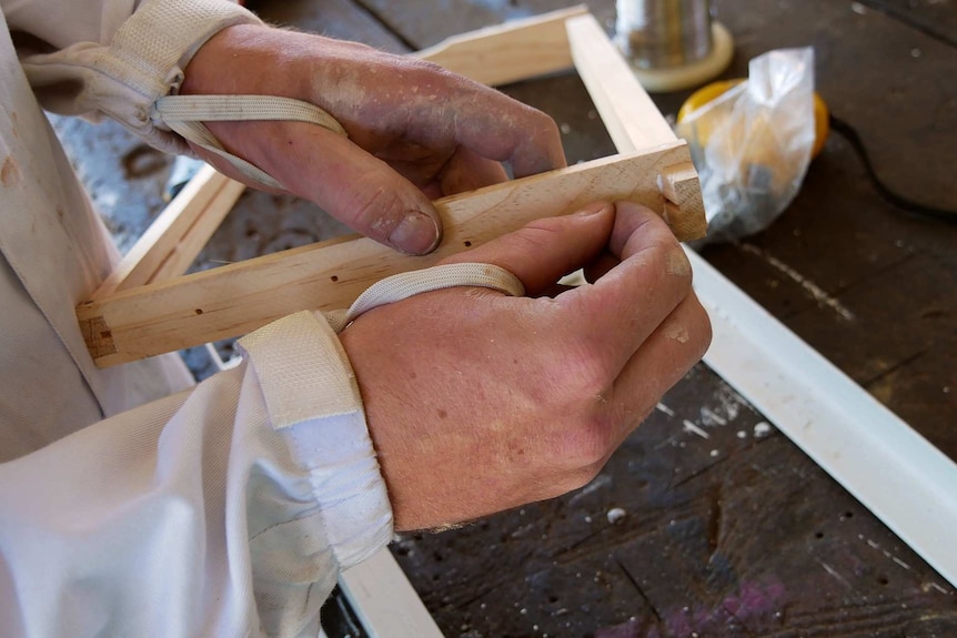 Close of of hands working on building a bee hive