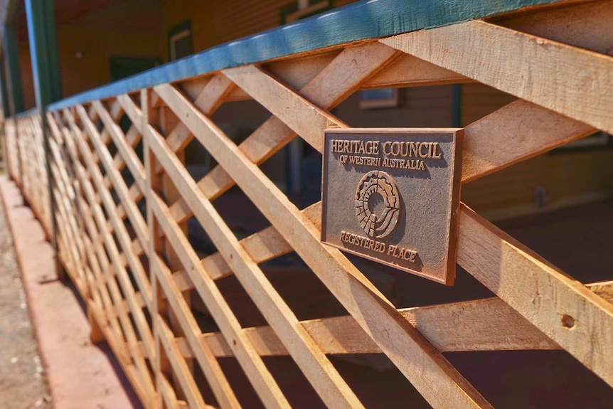 A close-up of lattice work outside a building covered in red dust.