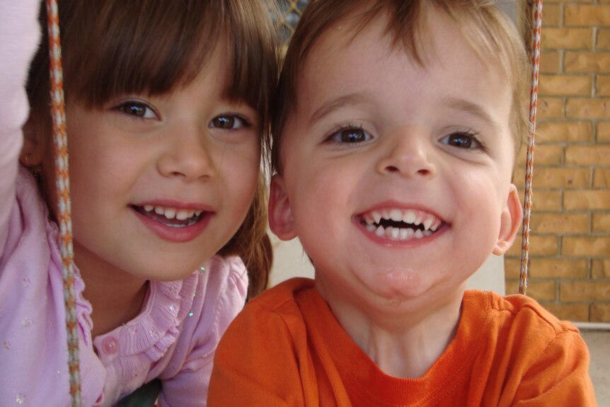 Two kids smiling directly into the camera. A boy and a girl. 