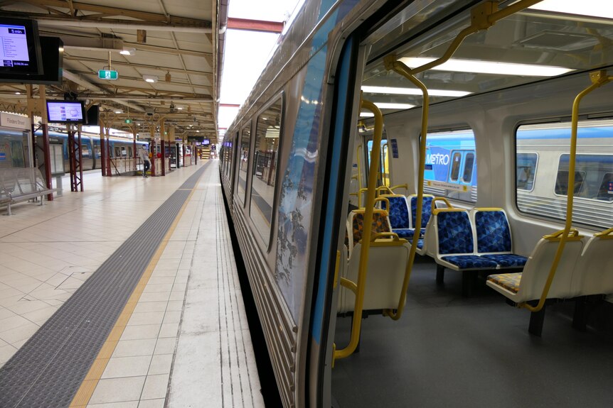 An empty train with the doors open sits at an empty train platform.