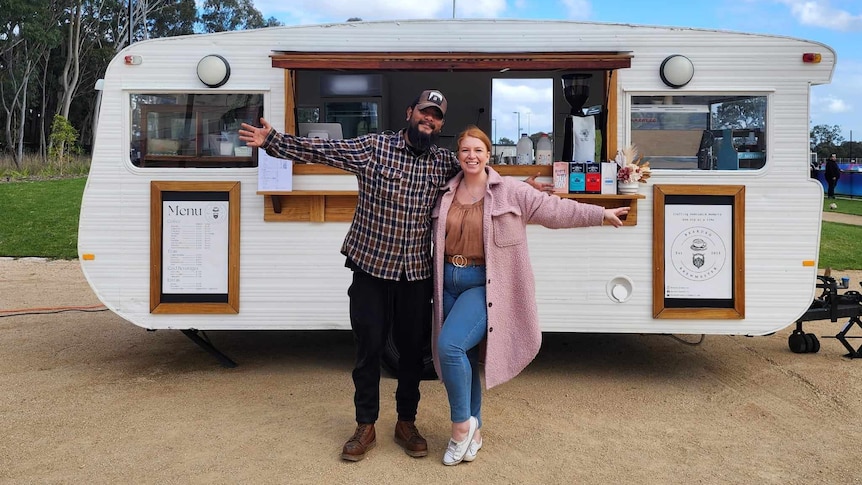 A couple posing in front of their coffee caravan business.