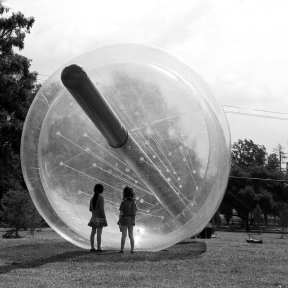 Two kids stand in front of a giant plastic cup installation.