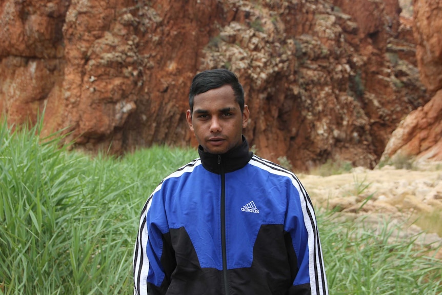 Young man standing in Alice Springs bushland looking into camera