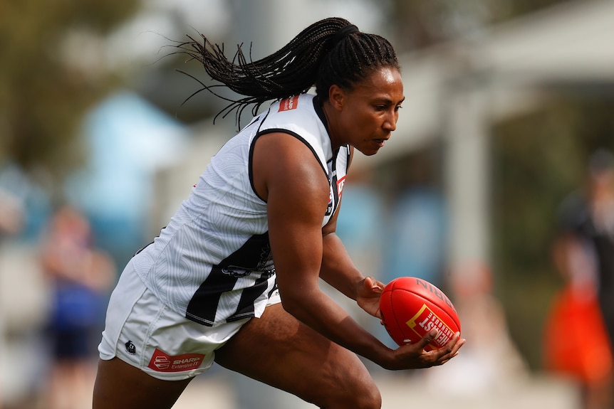 A Collingwood AFLW player runs with the ball against the Western Bulldogs.