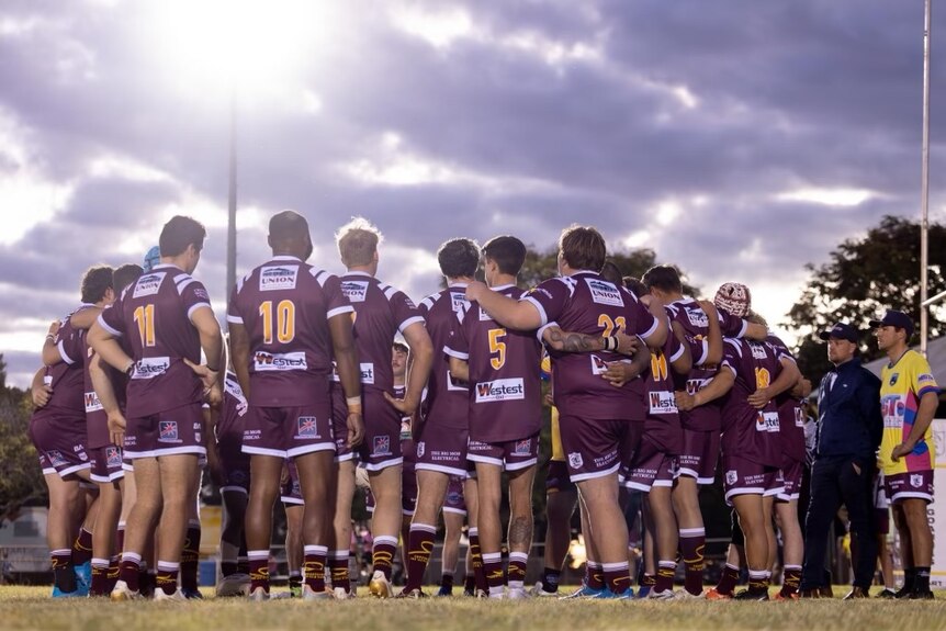 Outback rugby league side do a team huddle 