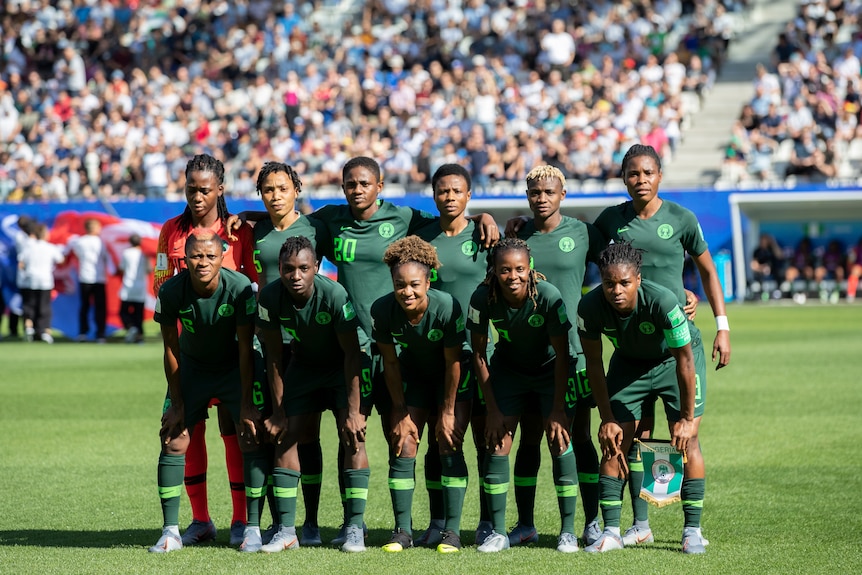 A women's soccer team wearing dark green poses for a photo before a big game