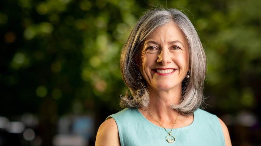 A woman with grey hair wearing a blue top