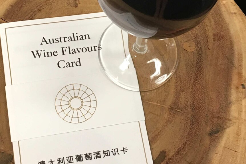 A glass of red wine next to a wine flavour card.