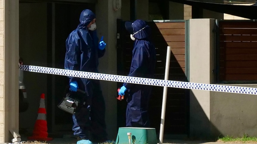 Forensic police in blue jumpsuits and masks outside a home cordoned off with police tape.
