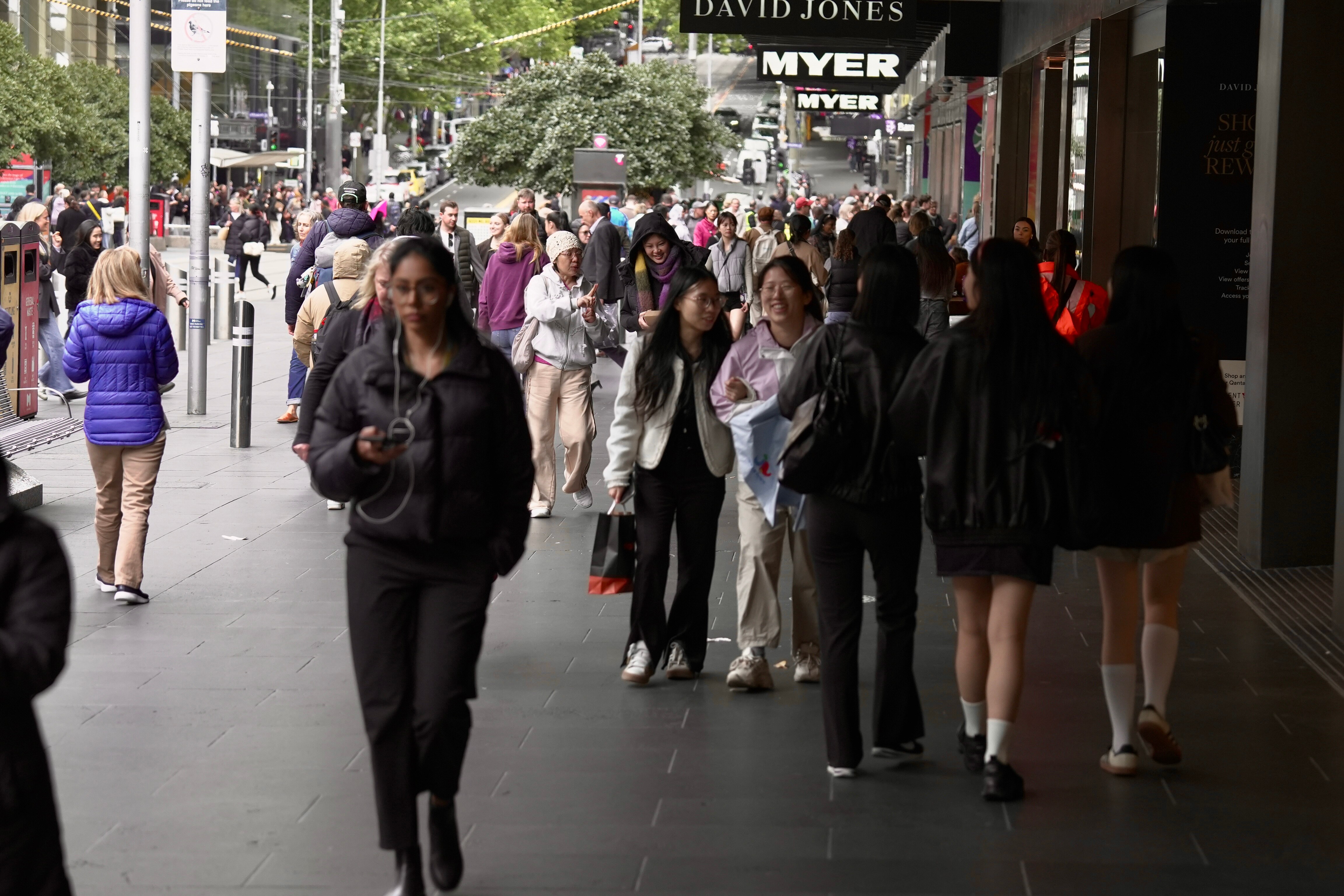 Uma multidão na calçada segurando pôsteres de Myers e David Jones.