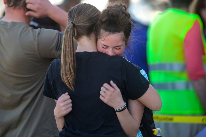 Two young girls embrace after a school shooting.