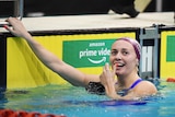 A smiling Ariarne Titmus puts her hand to her face in delight after winning a race at Australia's Olympic swim trials