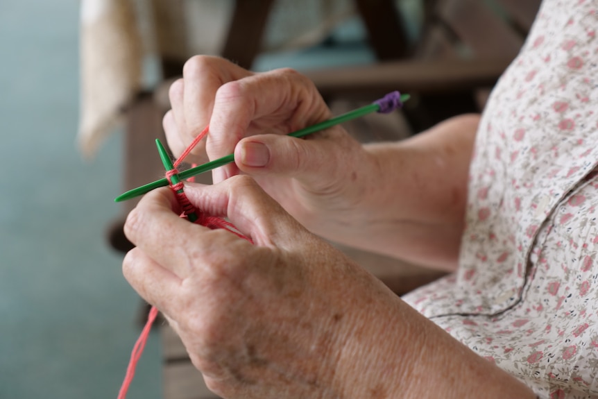 A woman's hands holding wool and knitting needles.