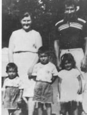 A black and white photo of two adults and three young children, posing.