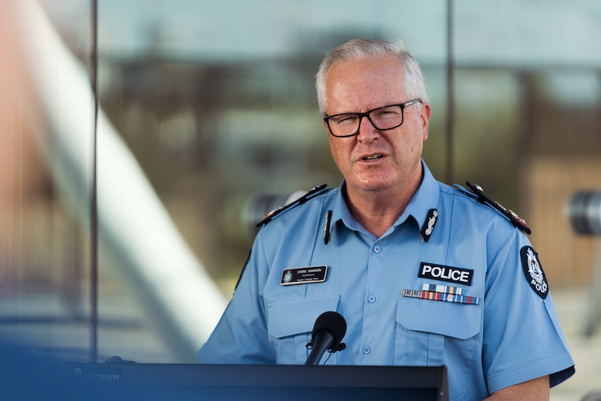 The commissioner stands in front of a podium. He wears his police uniform.