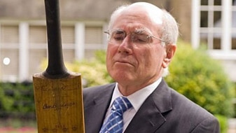 File photo: John Howard with a cricket bat (AFP)