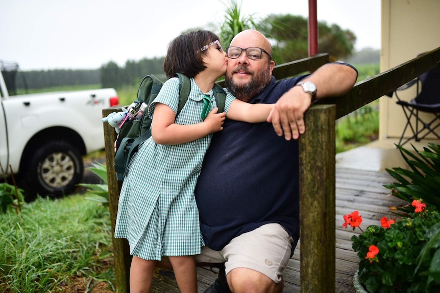A little girl kissing a man in front of a house